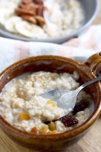 Taking a bite of a bowl of creamy make-ahead steel cut oats with raisins and maple syrup