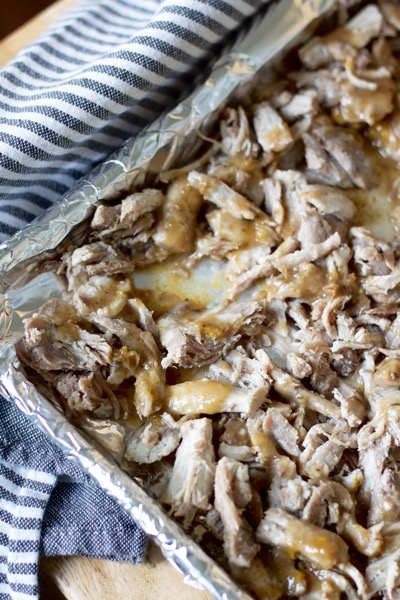 The glaze gets drizzled on the shredded pork before the carnitas for a crowd go under the broiler.