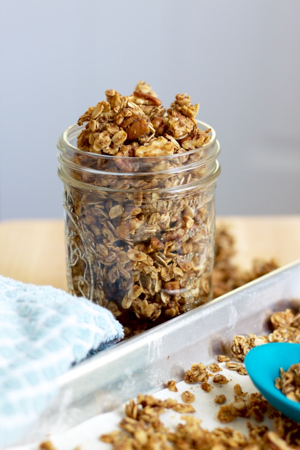 A mason jar overflowing with nutty coconut granola clusters