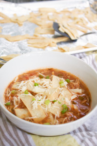 a loaded bowl of crockpot chicken tortilla soup with crunchy baked tortilla strips