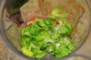 adding cilantro to the blender for diy salsa in the blender