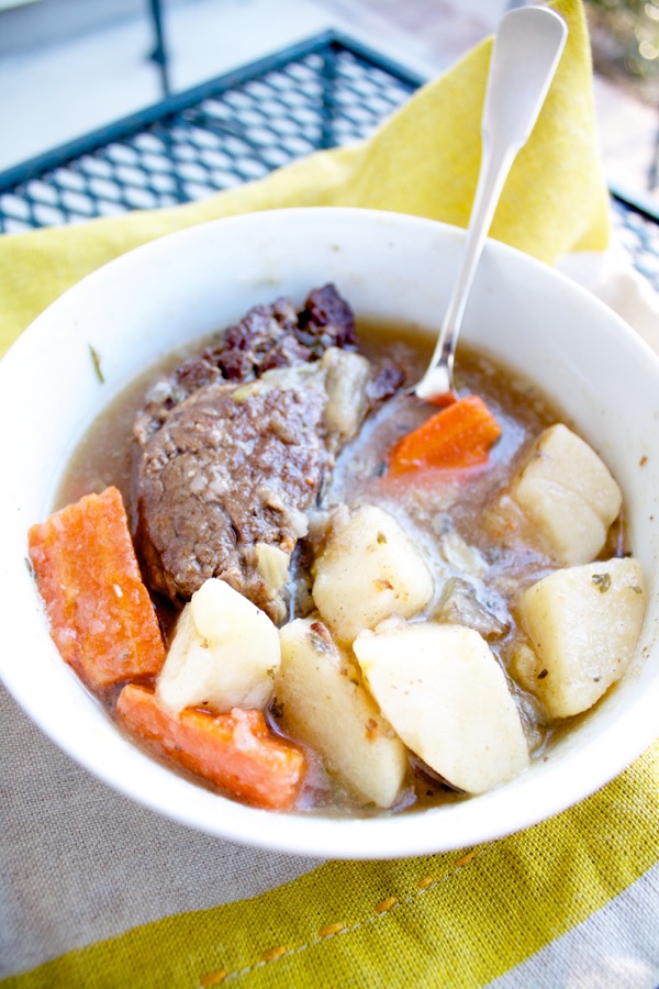 a bowl of pot roast with tender meat, potatoes, and carrots