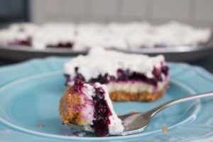 Blueberry cheesecake bars are four layers of delicious: graham cracker crust, cheesecake, blueberry pie filling, and fluffy whipped cream.