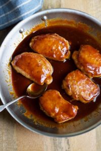 pork chops smothered with honey bbq sauce in a skillet