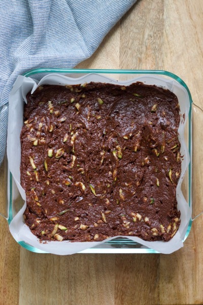 flourless double chocolate zucchini cake in a parchment-lined baking pan ready for the oven