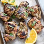 a sheet pan with citrus herb marinated grilled chicken with basil and orange slices