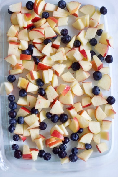 a glass pan of cut up apples and blueberries